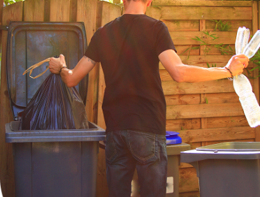 Personne de dos qui trie ses poubelles